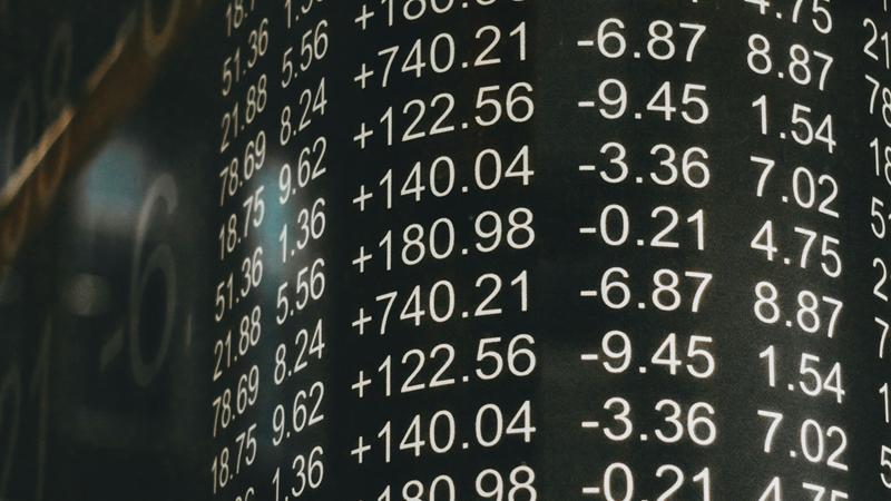 Columns of white numbers with plus and minus changes on a dark glass board