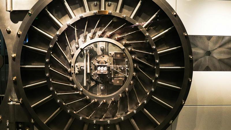 A large round steel vault door with radial locking bolts